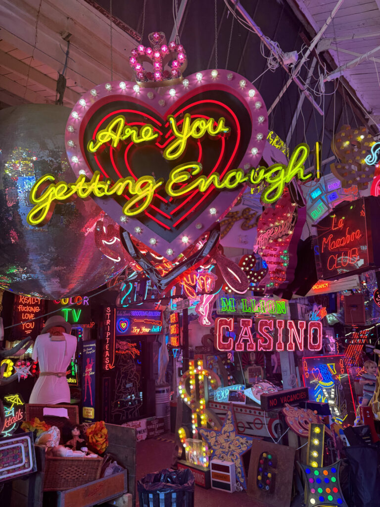A yellow neon sign saying Are You Getting Enough at God's Own Junkyard - a museum dedicated to neon signs.