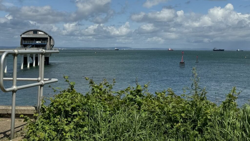 A view out to see with Bembridge Lifeboat Station, Isle of Wight in the distance. A sunny day with a few clouds in the sky.