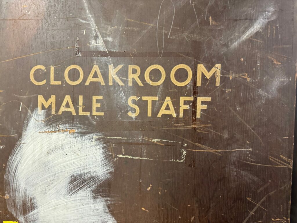 A cloakroom sign on a wooden door. The rooms here were added when the platform closed.