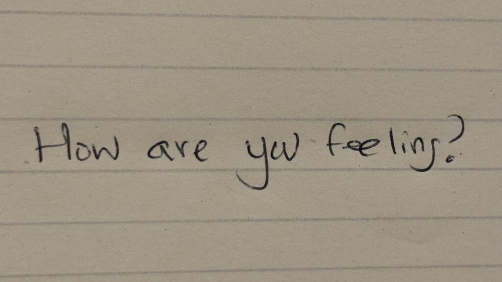 The words "how are you feeling" hand written on a yellow legal notepad.