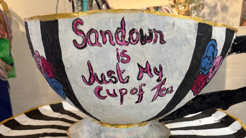 A tea cup and saucer hat. The slogan "Sandown Is Just My Cup of Tea"s is written on the front of the cup.